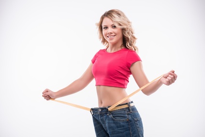 Slim waist of young woman in big jeans with measuring tape showi